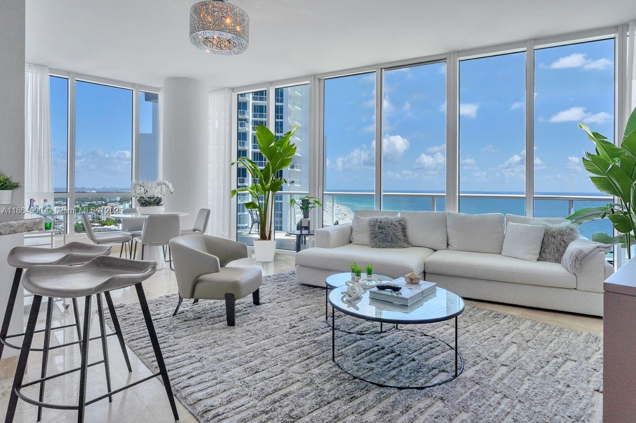 A bright living room features a white sectional sofa, glass coffee tables, and floor-to-ceiling ocean views — 100 S Pointe Dr # 2208, Miami Beach FL 33139, MIAMI BEACH, FL