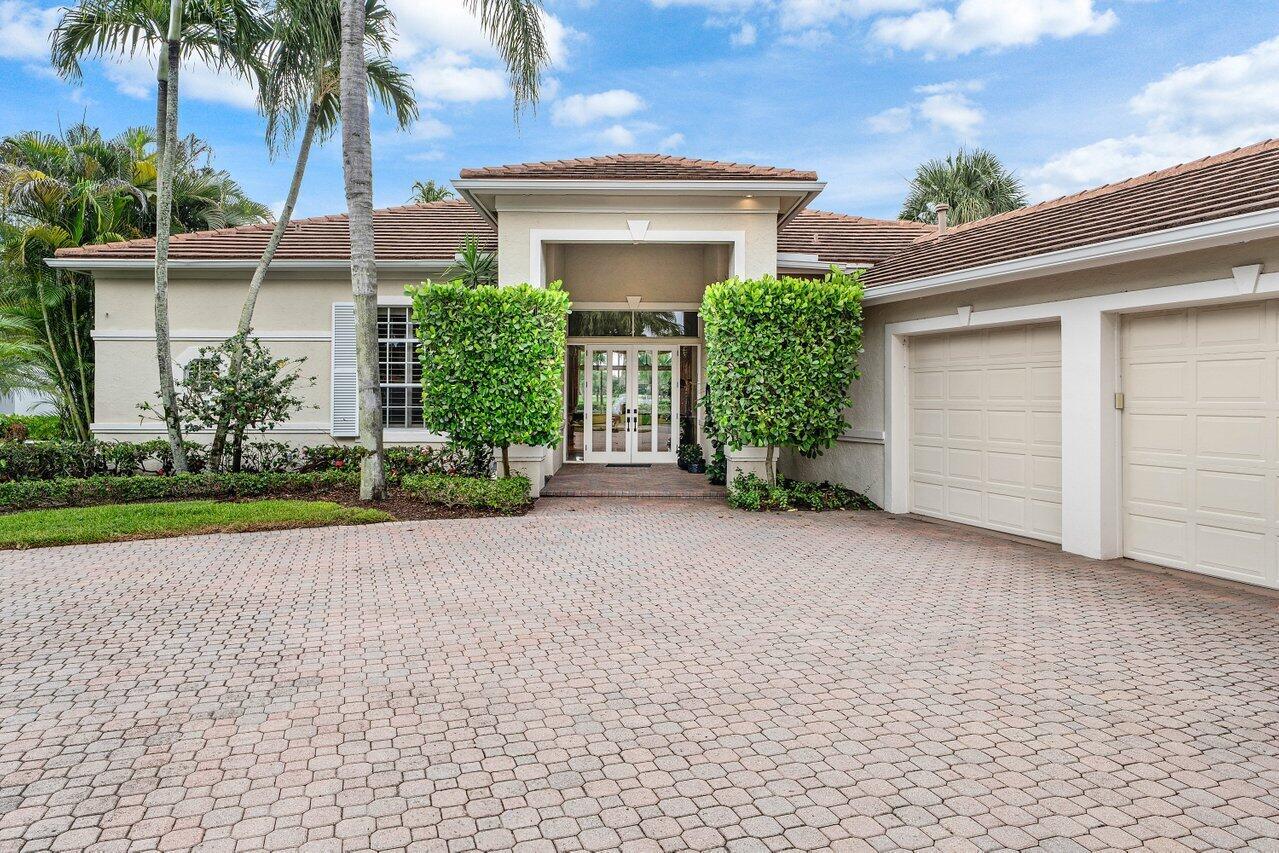 A single-story house with a paved driveway, two garage doors, and a covered front entrance — 118 W Village Way, Jupiter FL 33458, JUPITER, FL