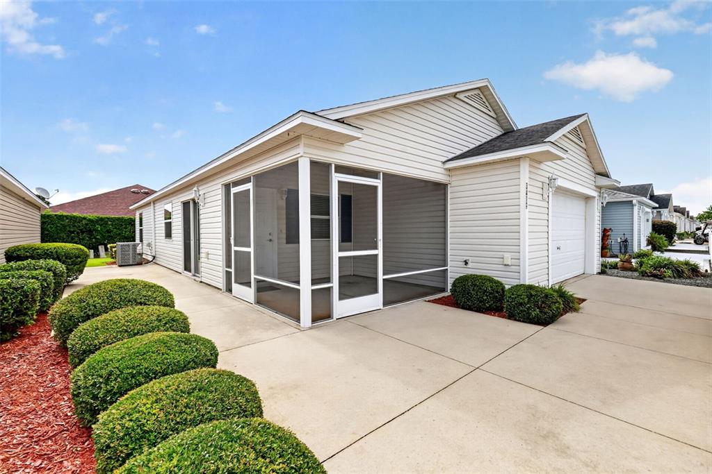A single-story house with light siding, a screened-in porch, and a concrete driveway — 3419 CARRABELLE COURT, THE VILLAGES, FL