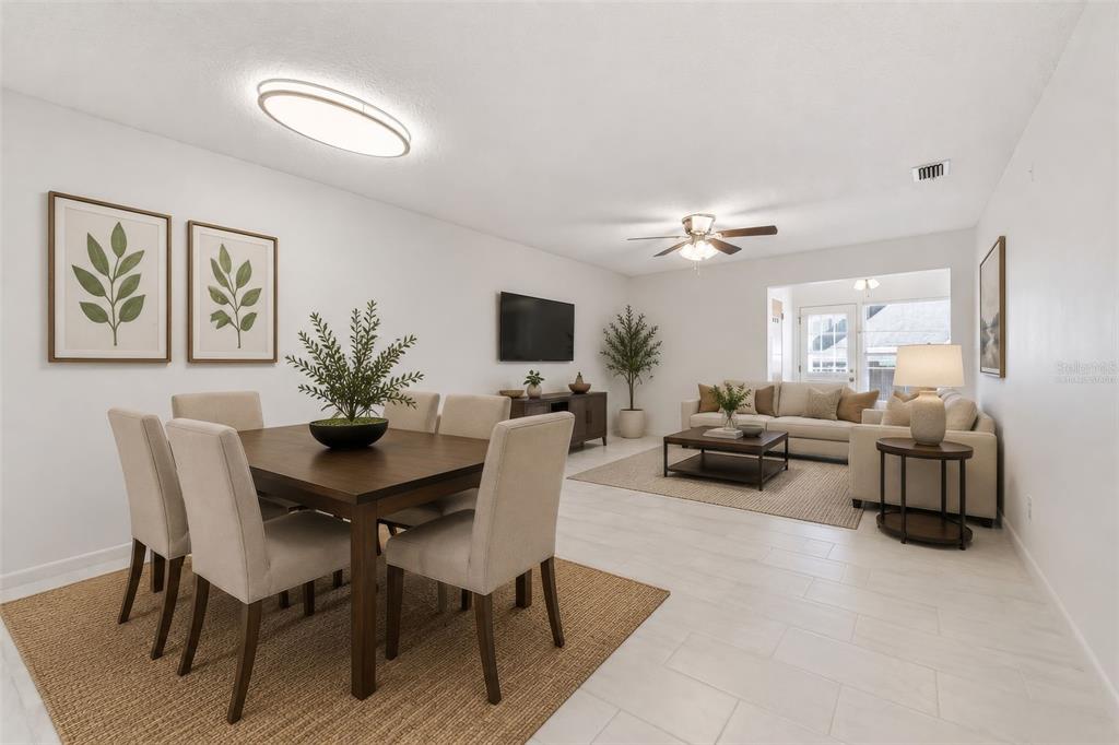An open-concept living and dining area features light tile floors, neutral furniture, and wall art — 151 N HILL AVENUE UNIT 100, DELAND, FL