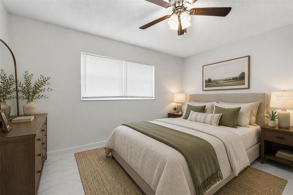 A bedroom features a bed with olive green accents, a wooden dresser, and a ceiling fan — 151 N HILL AVENUE UNIT 100, DELAND, FL
