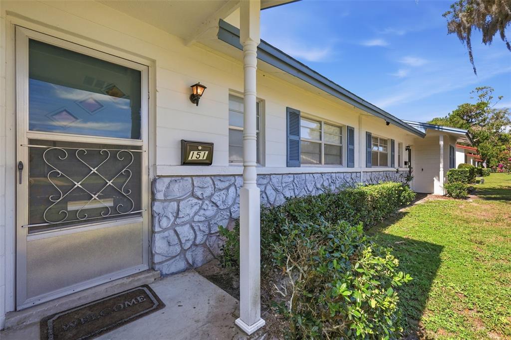 The exterior of a house features a white door, stone siding, and a front porch — 151 N HILL AVENUE UNIT 100, DELAND, FL