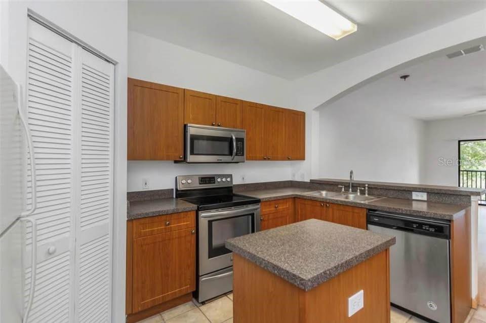 A kitchen features wood cabinets, stainless steel appliances, a small island, and a breakfast bar — 2139 CHIANTI PLACE UNIT 5-0152, PALM HARBOR, FL