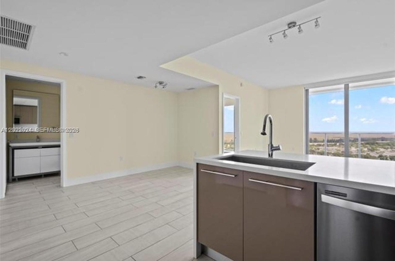 A kitchen island with a sink overlooks an open living area with tile floors — 2000 Metropica Way # 2202, Sunrise FL 33323, SUNRISE, FL