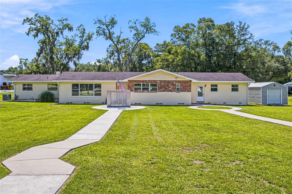 A single-story house with a brick facade, light yellow siding, and a front walkway — 110 NE 5TH STREET, WILLISTON, FL