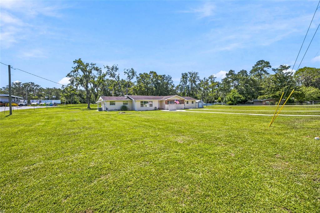 A single-story house with a light-colored exterior sits on a large, open grassy lot — 110 NE 5TH STREET, WILLISTON, FL