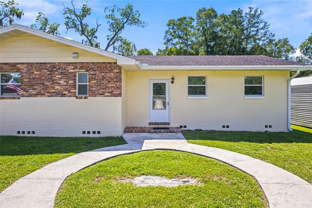 A single-story house with a yellow painted brick exterior and a circular concrete walkway — 110 NE 5TH STREET, WILLISTON, FL