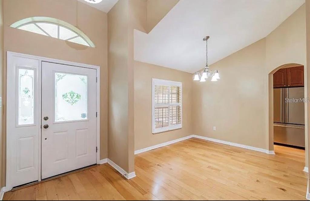 An entryway with light wood floors, a white front door, and an adjacent dining area — 4914 N MENDENHALL DRIVE, TAMPA, FL
