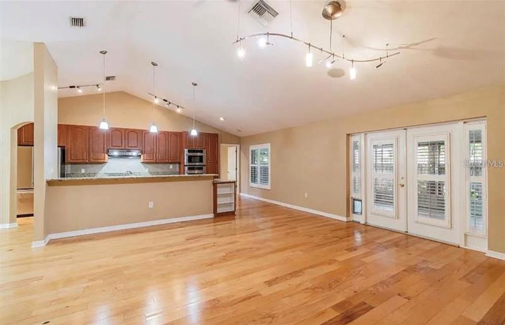 An open-concept kitchen and living area features hardwood floors, vaulted ceilings, and wooden cabinetry — 4914 N MENDENHALL DRIVE, TAMPA, FL