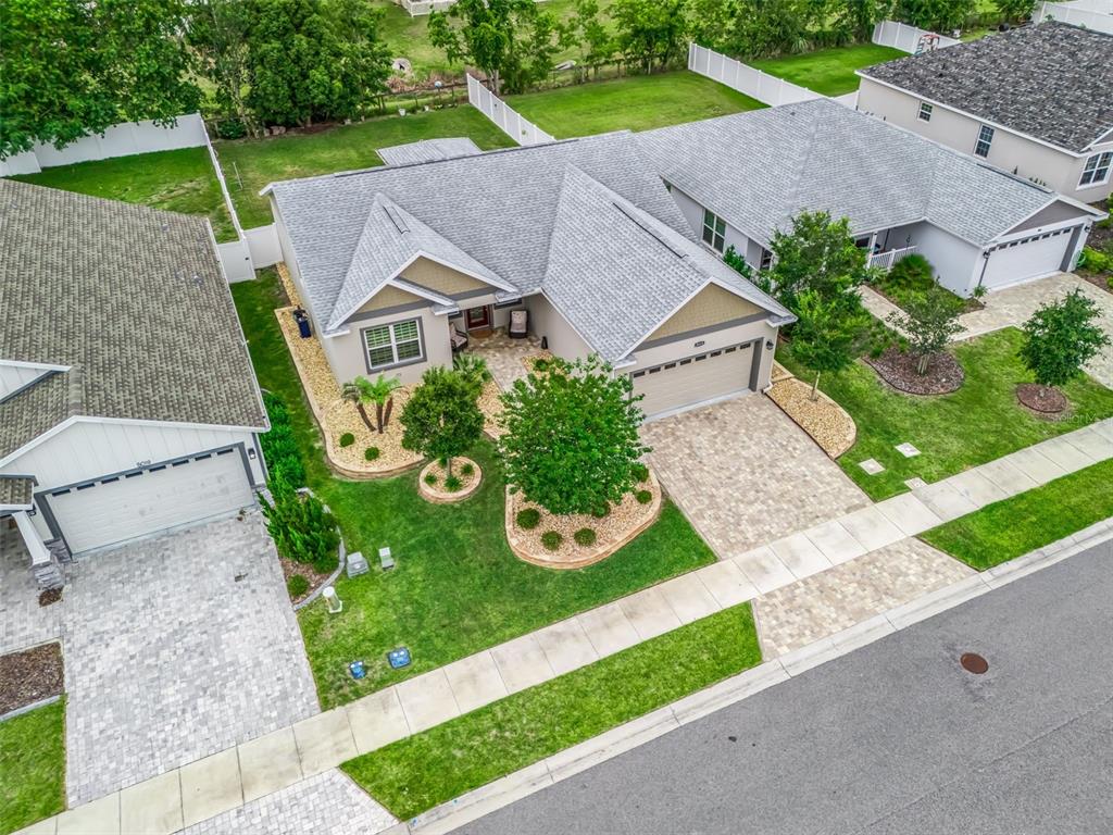 An aerial view of a suburban house with a paved driveway, landscaping, and gray roof — 5015 NE 125TH LOOP, OXFORD, FL