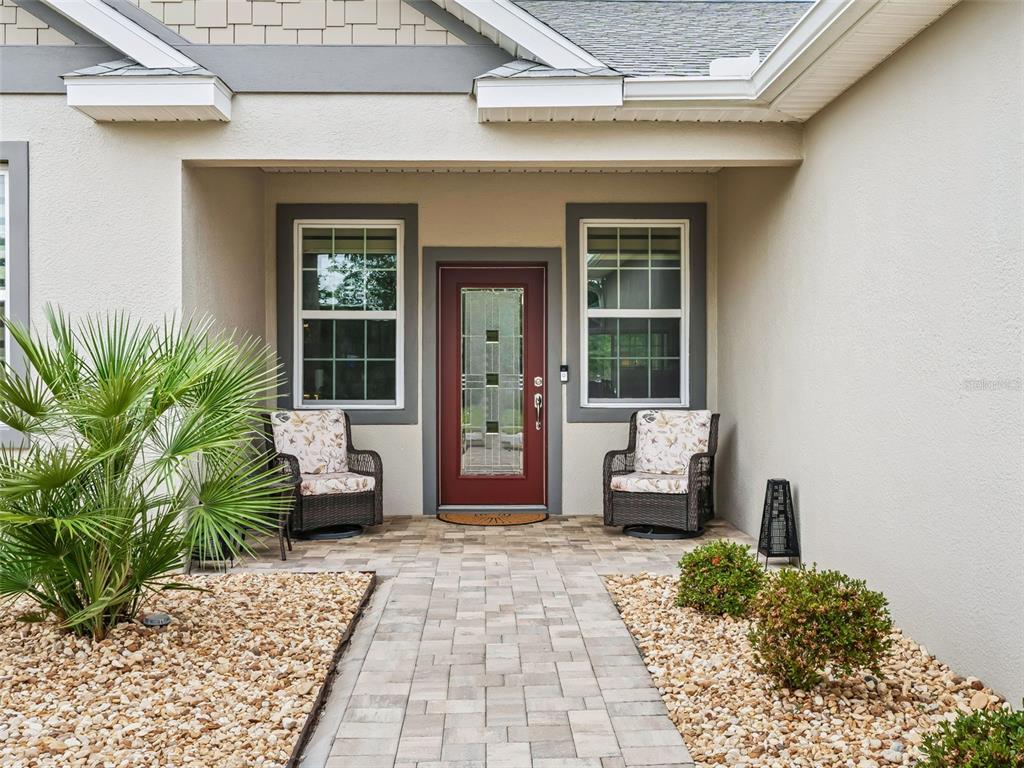 A front entrance features a red door, two wicker chairs, and a paved walkway — 5015 NE 125TH LOOP, OXFORD, FL