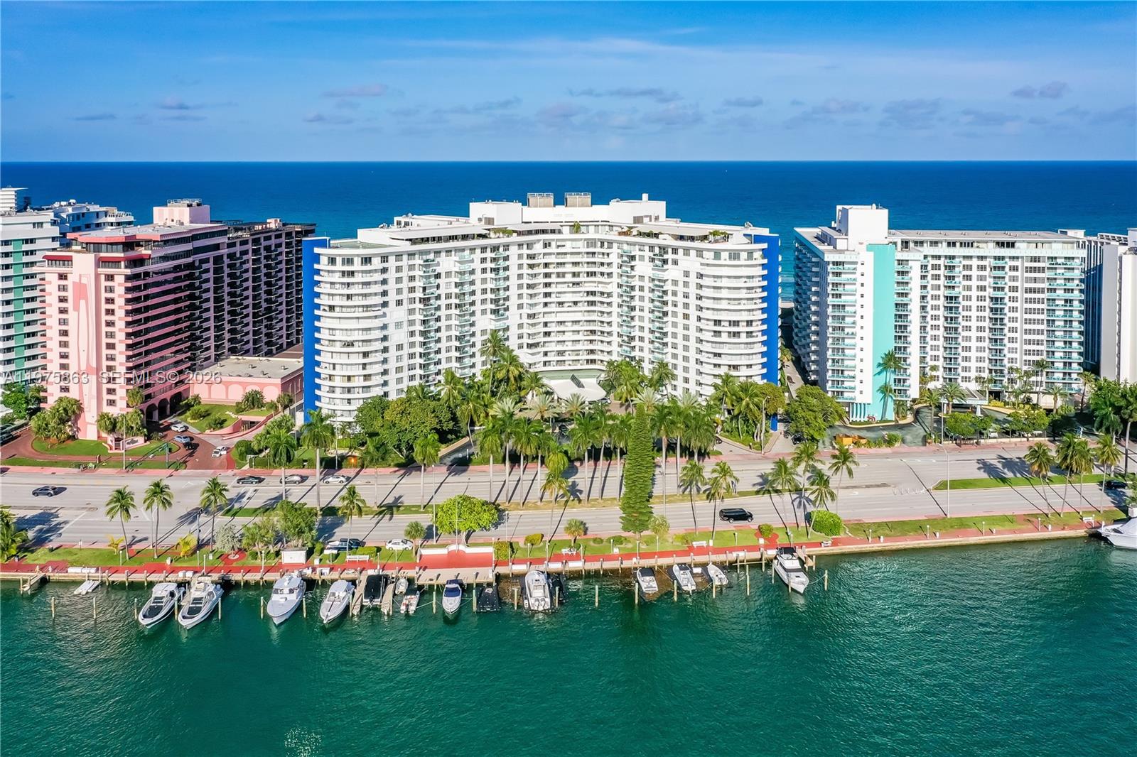 An aerial view of a curved waterfront condominium building with a private boat dock — 5161 Collins Ave # 1012, Miami Beach FL 33140, MIAMI BEACH, FL