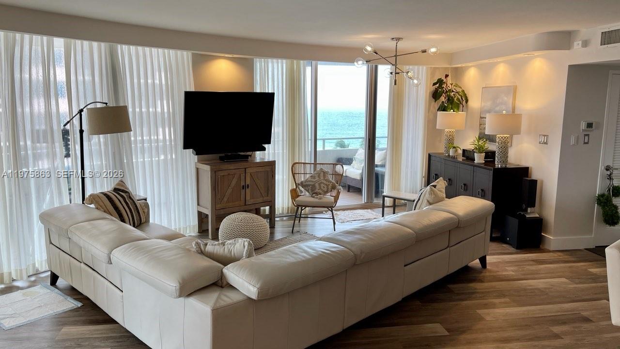 A living room features a white sectional sofa, a television on a wooden cabinet, and ocean views — 5161 Collins Ave # 1012, Miami Beach FL 33140, MIAMI BEACH, FL