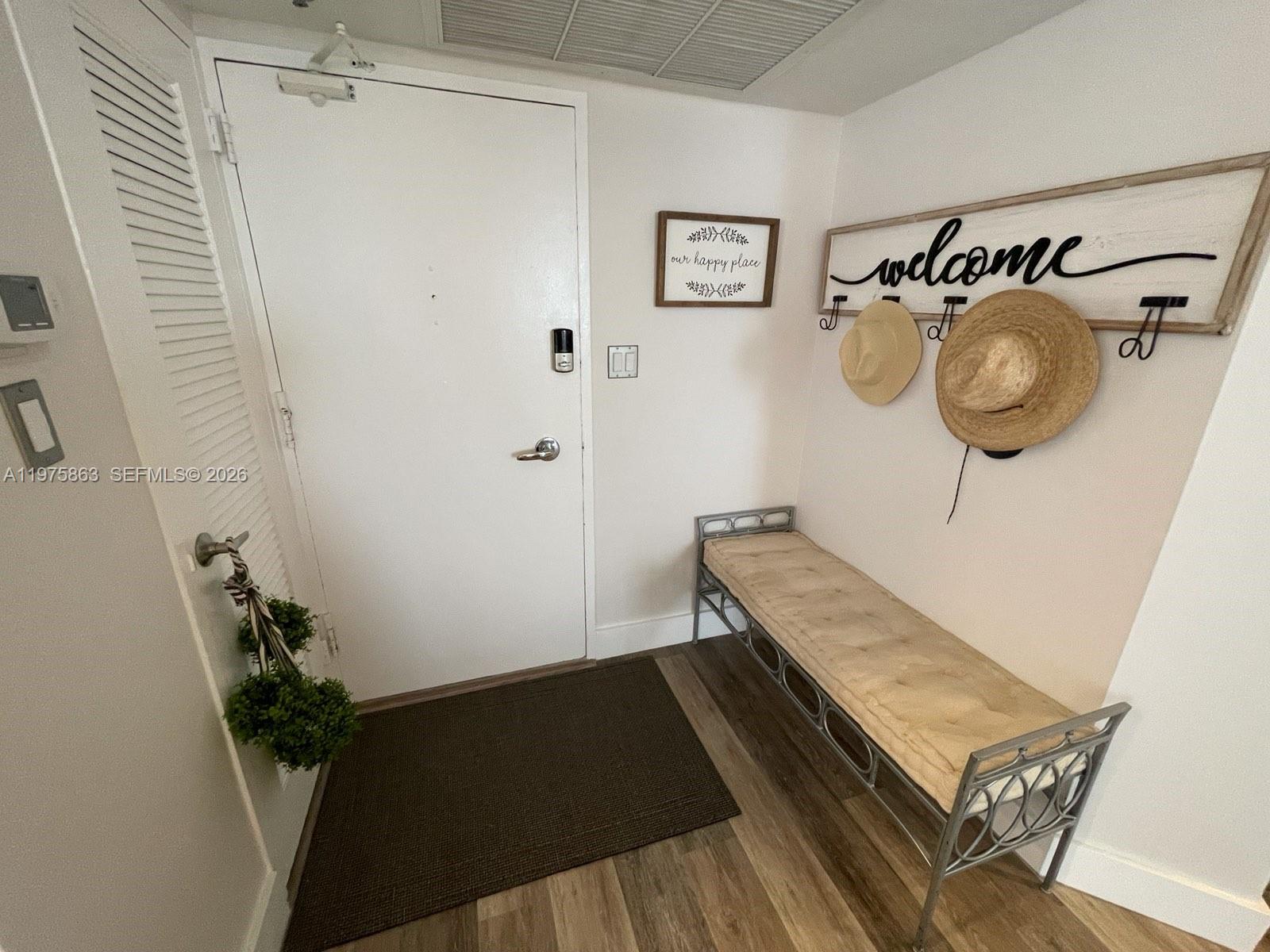 An entryway features a white door, a metal bench, and a welcome sign with hooks — 5161 Collins Ave # 1012, Miami Beach FL 33140, MIAMI BEACH, FL
