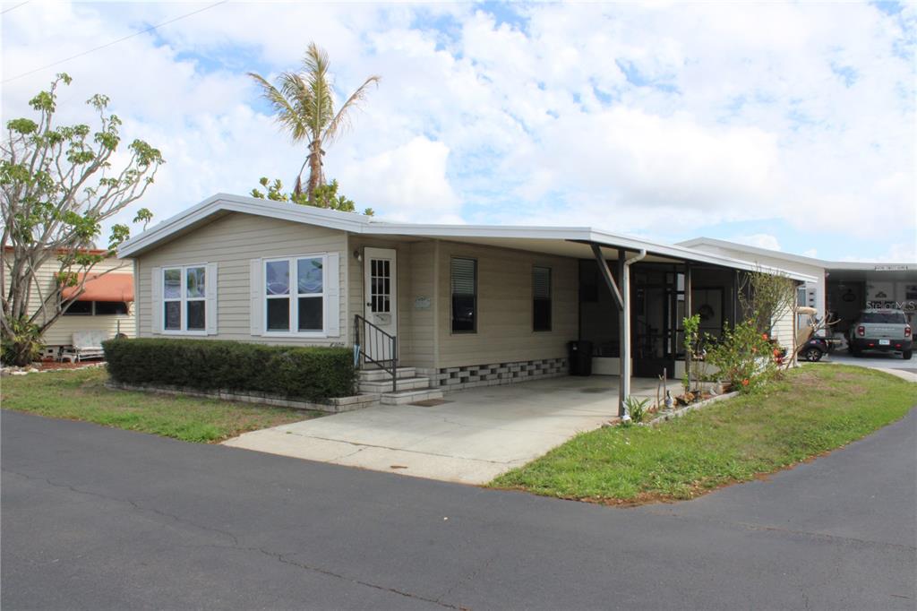 A single-story manufactured home with beige siding, a carport, and a small front porch — 6807 MOUNT PLEASANT ROAD NE UNIT 51, ST PETERSBURG, FL