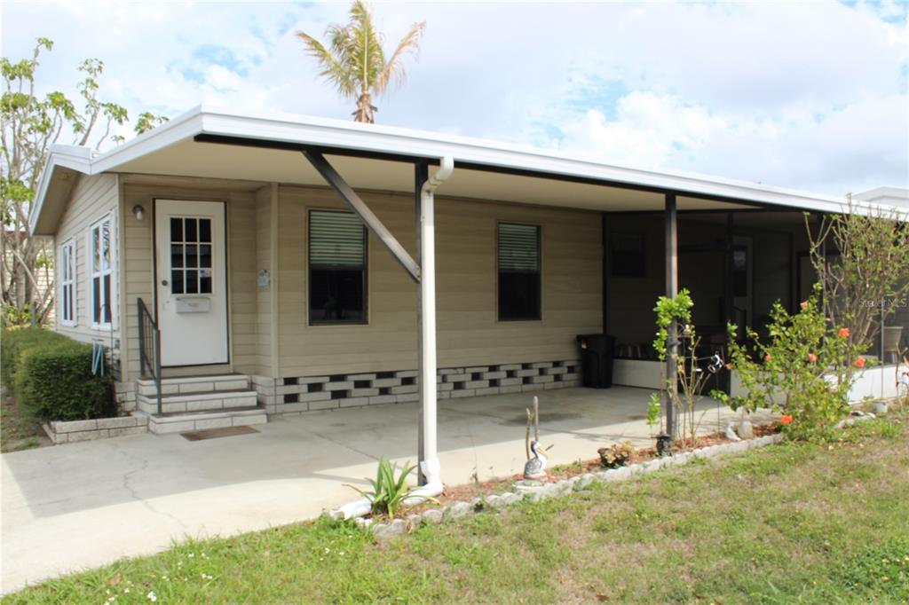 A single-story mobile home with a carport, tan siding, and a small front porch — 6807 MOUNT PLEASANT ROAD NE UNIT 51, ST PETERSBURG, FL