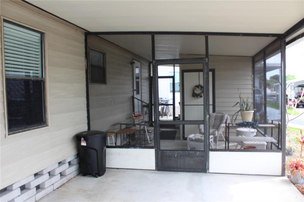 A covered patio features a screened-in enclosure, concrete flooring, and a black trash can — 6807 MOUNT PLEASANT ROAD NE UNIT 51, ST PETERSBURG, FL