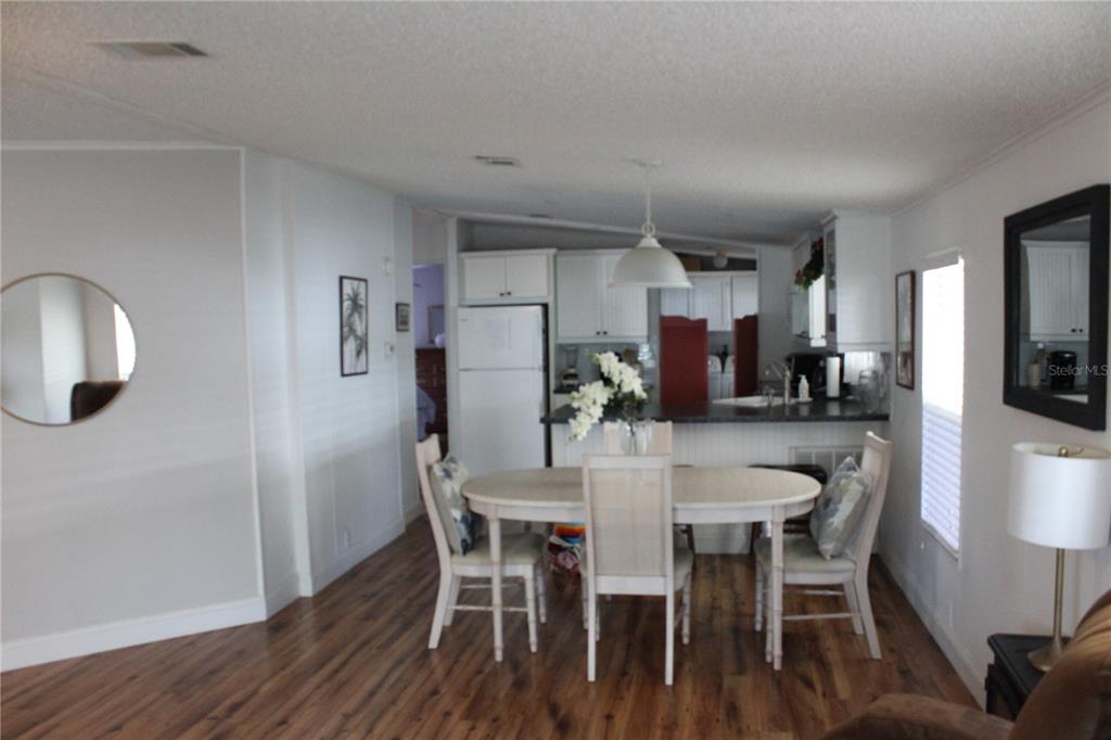 A dining area with a wooden table and chairs sits in front of a kitchen — 6807 MOUNT PLEASANT ROAD NE UNIT 51, ST PETERSBURG, FL