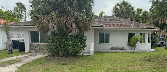 A single-story house with a tiled roof, white exterior, and a large palm tree — 56 LAUREL STREET, CLEARWATER BEACH, FL