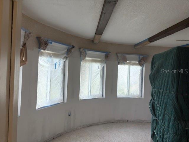 A room with curved walls, three windows covered in plastic, and exposed wooden ceiling beams — 56 LAUREL STREET, CLEARWATER BEACH, FL