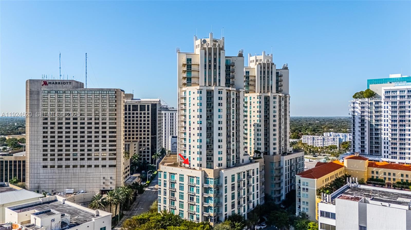 An exterior view of a tall residential building with a red arrow pointing toward a balcony — 9055 SW 73 CT # 809, Miami FL 33156, MIAMI, FL