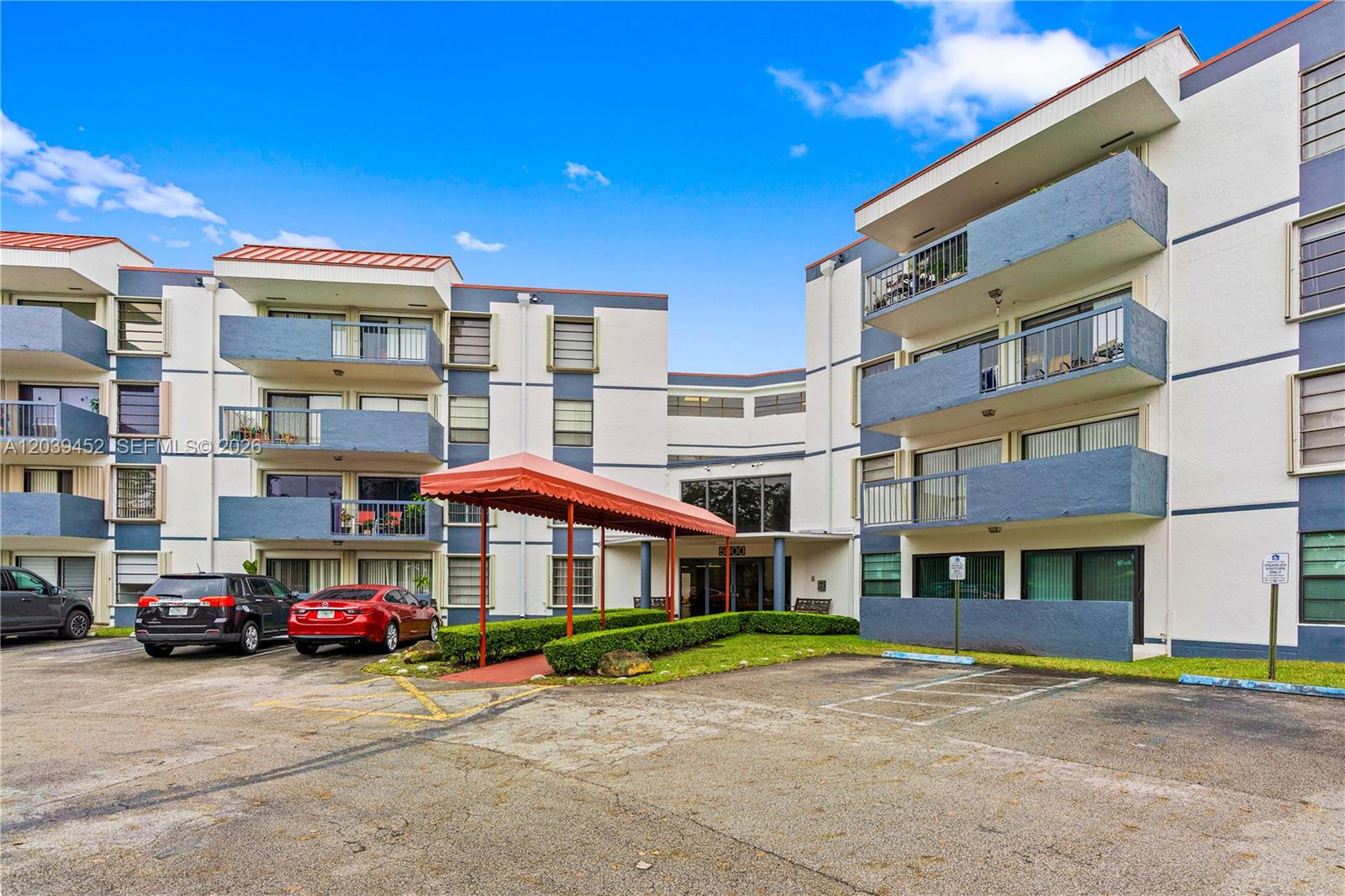 A multi-story apartment building features blue balconies, a red awning, and a paved parking lot — 5900 SW 127th Ave # 3119, Miami FL 33183, MIAMI, FL