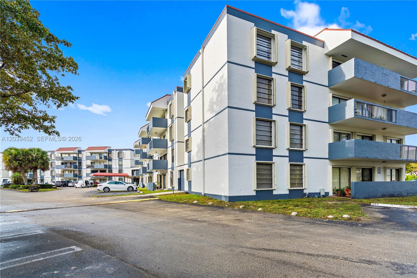 A multi-story apartment building with white and blue exterior walls features several balconies — 5900 SW 127th Ave # 3119, Miami FL 33183, MIAMI, FL