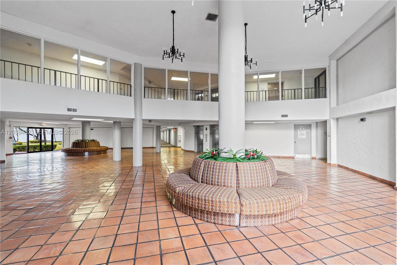 A spacious lobby features terracotta tile floors, a central circular bench, and a mezzanine level — 5900 SW 127th Ave # 3119, Miami FL 33183, MIAMI, FL