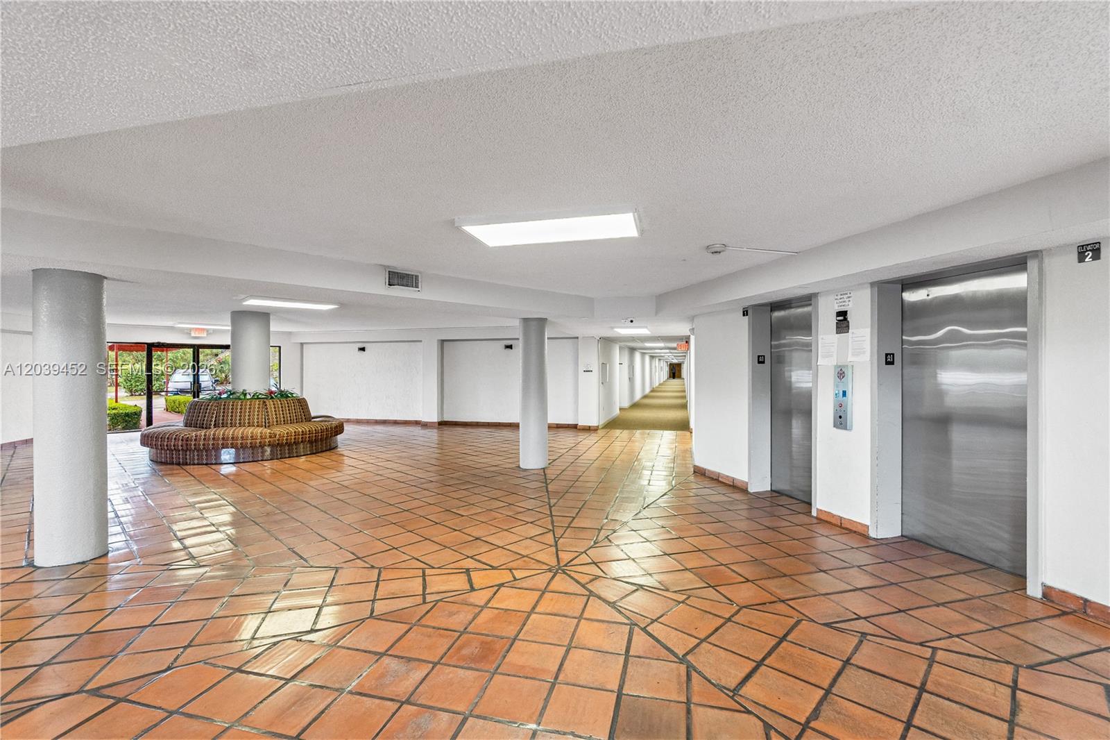 A spacious building lobby features terracotta tile flooring, two elevators, and a curved seating area — 5900 SW 127th Ave # 3119, Miami FL 33183, MIAMI, FL
