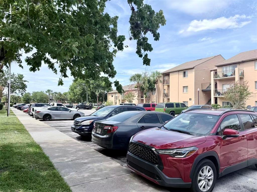 A parking lot with several cars parked in front of multi-story apartment buildings — 5226 VIA HACIENDA CIRCLE UNIT A214, ORLANDO, FL