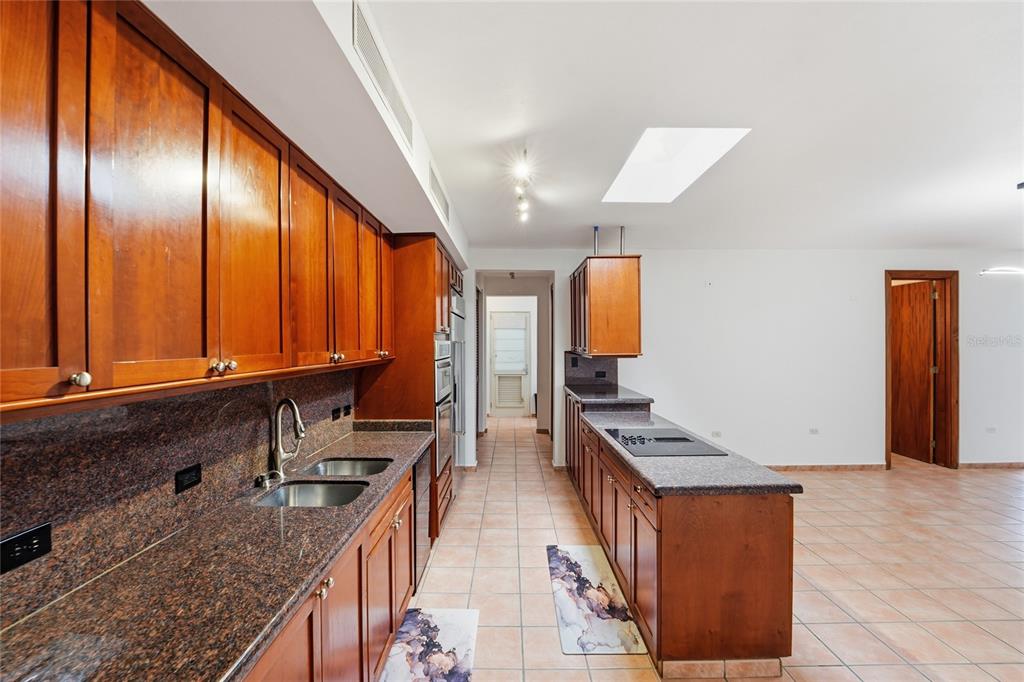 A kitchen features wood cabinets, granite countertops, tile flooring, and a central skylight — 182 DORADO BEACH EAST, DORADO, PR