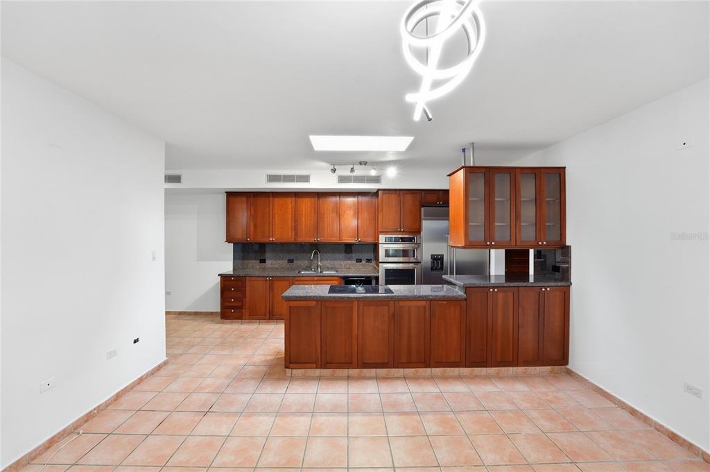 A kitchen with wooden cabinets, dark countertops, a central island, and tiled flooring — 182 DORADO BEACH EAST, DORADO, PR