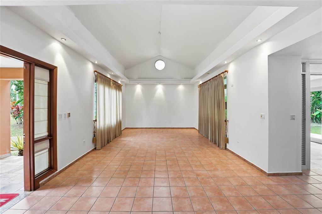 An empty room with vaulted ceilings, tile floors, and large windows covered by beige curtains — 182 DORADO BEACH EAST, DORADO, PR