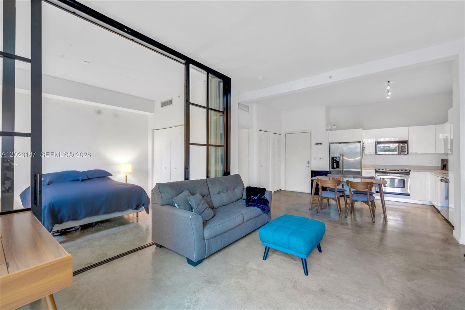 An open-concept studio apartment features a bedroom behind glass partitions, a sofa, and kitchen — 234 NE 3rd St # 1108, Miami FL 33132, MIAMI, FL