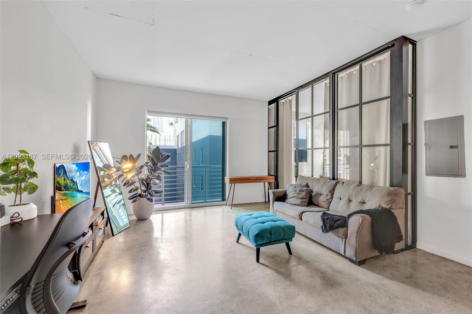 A living room features concrete floors, a gray sofa, a blue ottoman, and glass partitions — 234 NE 3rd St # 1108, Miami FL 33132, MIAMI, FL