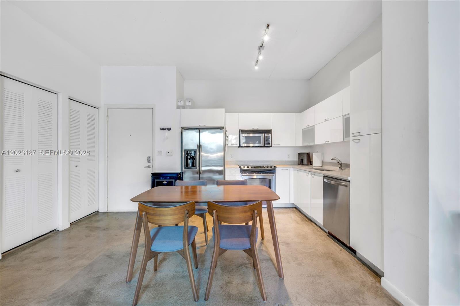 A kitchen and dining area features white cabinets, stainless steel appliances, and concrete flooring — 234 NE 3rd St # 1108, Miami FL 33132, MIAMI, FL