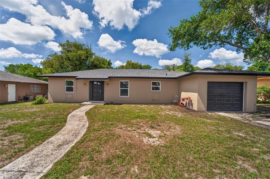 A single-story house with a tan exterior, dark trim, and an attached one-car garage — 7156 LOCKWOOD STREET, SPRING HILL, FL