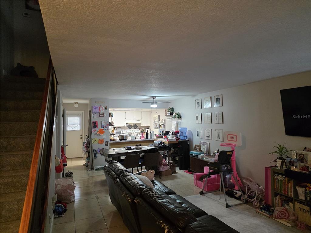 A living room and dining area with tile flooring, a staircase, and an open kitchen — 4823 W MCELROY AVENUE UNIT D211, TAMPA, FL