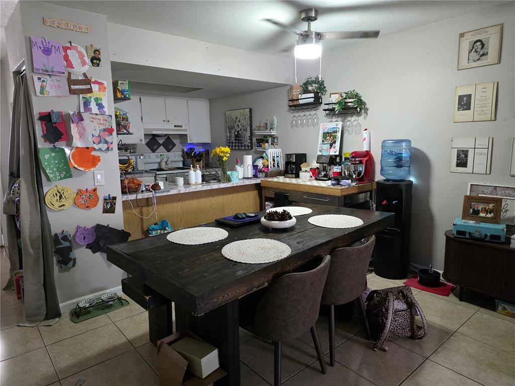 A dining area with a dark wooden table sits adjacent to an open kitchen — 4823 W MCELROY AVENUE UNIT D211, TAMPA, FL