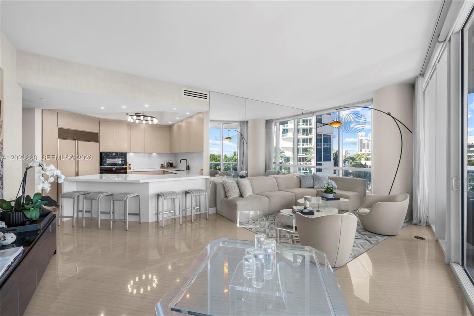 A modern open-concept living room and kitchen with light wood cabinetry and floor-to-ceiling windows — 100 S Pointe Dr # 509, Miami Beach FL 33139, MIAMI BEACH, FL