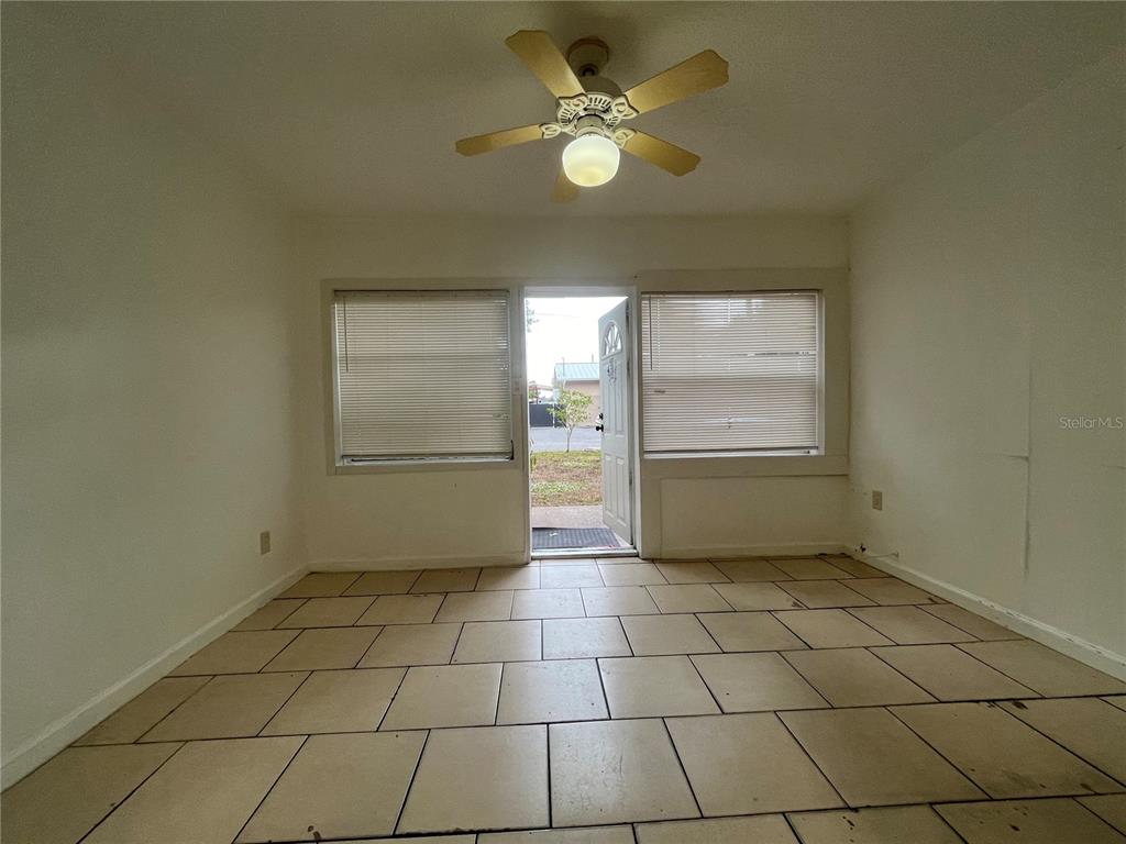 A room with light-colored tile flooring, a ceiling fan, and windows flanking an open door — 720 22ND AVENUE W, BRADENTON, FL