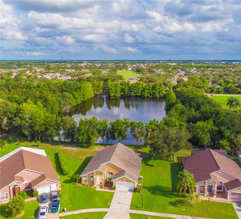 An aerial view shows three suburban houses situated in front of a large pond — 2663 GOLD DUST CIRCLE, KISSIMMEE, FL
