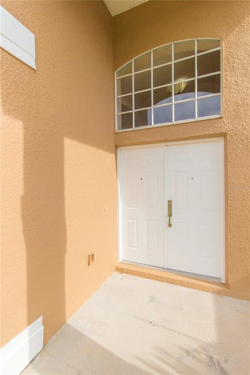 A beige stucco exterior features a double front door with a large arched window above — 2663 GOLD DUST CIRCLE, KISSIMMEE, FL