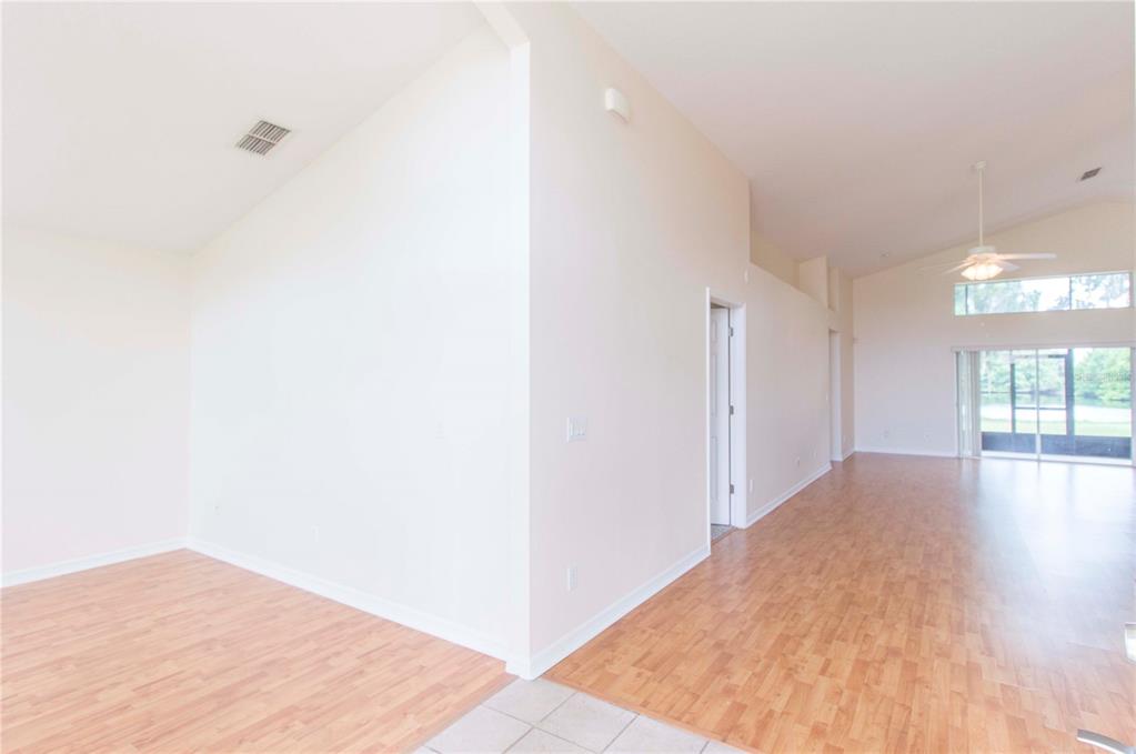 An interior view of a room with light wood-look flooring, vaulted ceilings, and sliding doors — 2663 GOLD DUST CIRCLE, KISSIMMEE, FL
