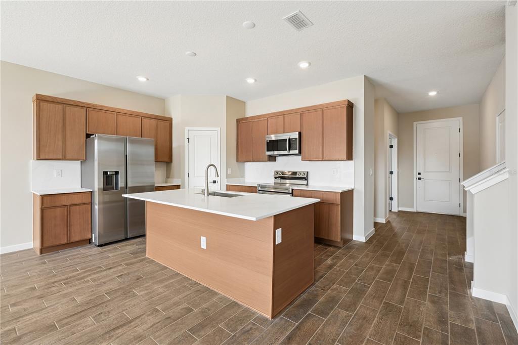 A kitchen features wood cabinets, stainless steel appliances, a white island, and brown tile flooring — 4488 NW 37TH STREET ROAD, OCALA, FL
