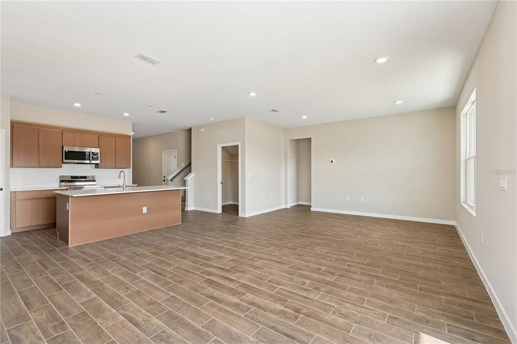 An open-concept kitchen and living area featuring light wood cabinets, an island, and tile flooring — 4488 NW 37TH STREET ROAD, OCALA, FL