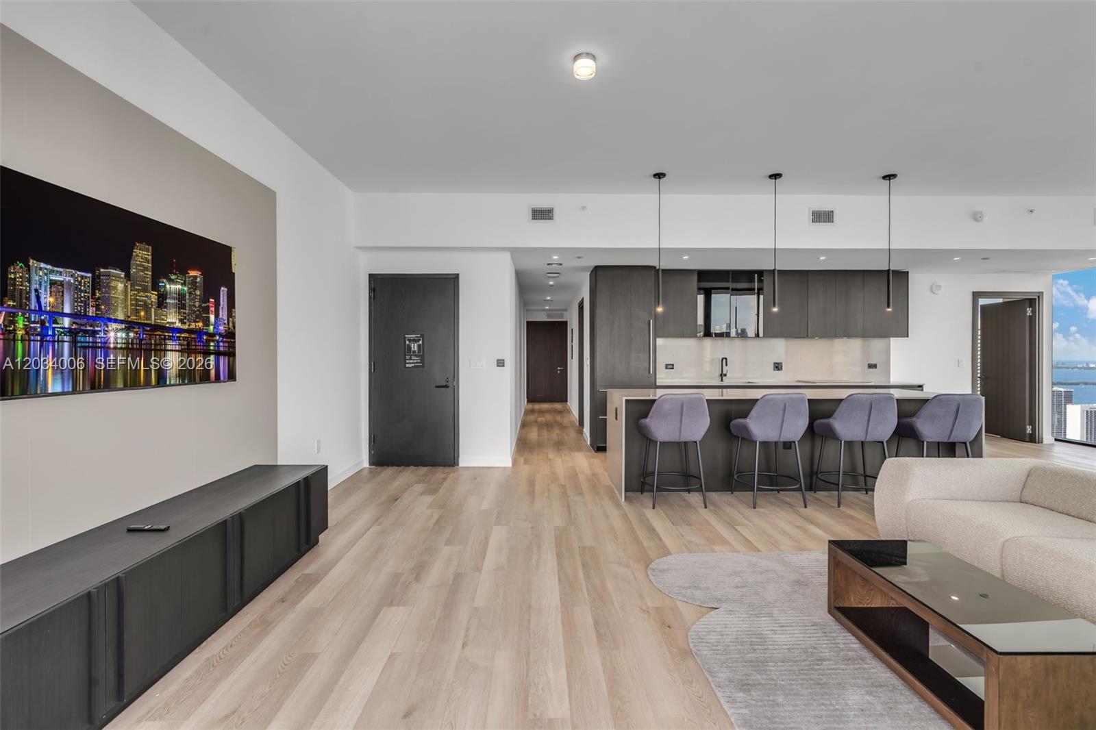 A modern open-concept living room and kitchen feature light wood floors and dark cabinetry — 20 NE 11th St # 5102, Miami FL 33132, MIAMI, FL