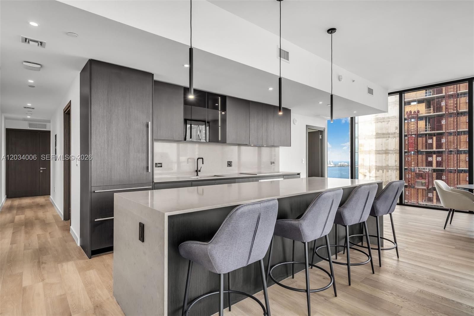 A modern kitchen features dark wood cabinetry, a large stone island, and four gray barstools — 20 NE 11th St # 5102, Miami FL 33132, MIAMI, FL