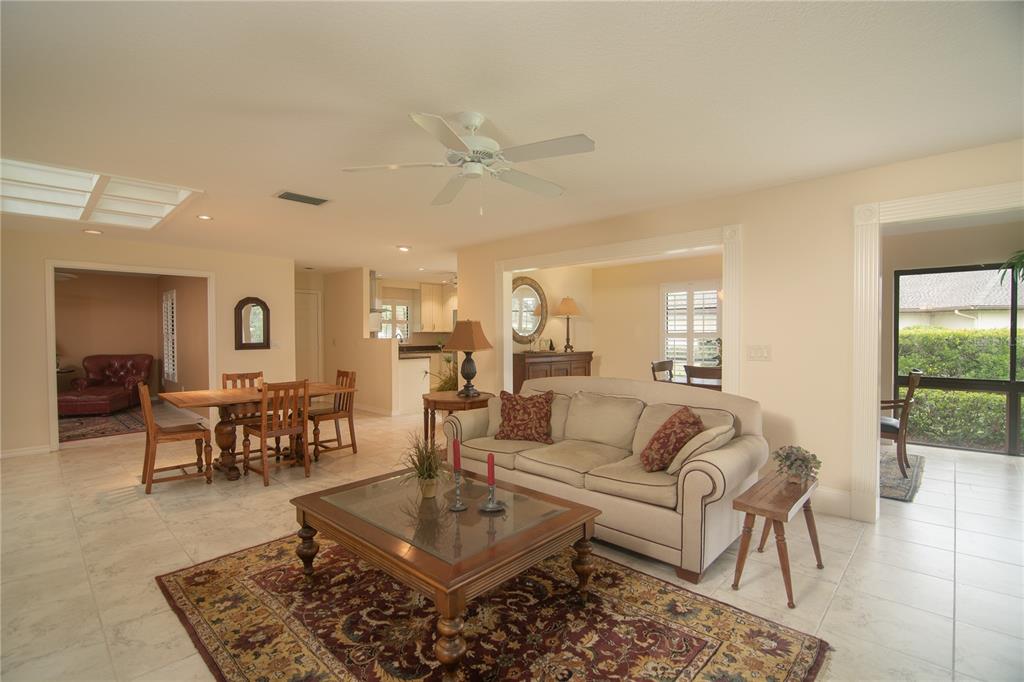 A living room with a beige sofa, wooden coffee table, and tile flooring — 7403 CARNOUSTIE DRIVE UNIT 7D, SARASOTA, FL