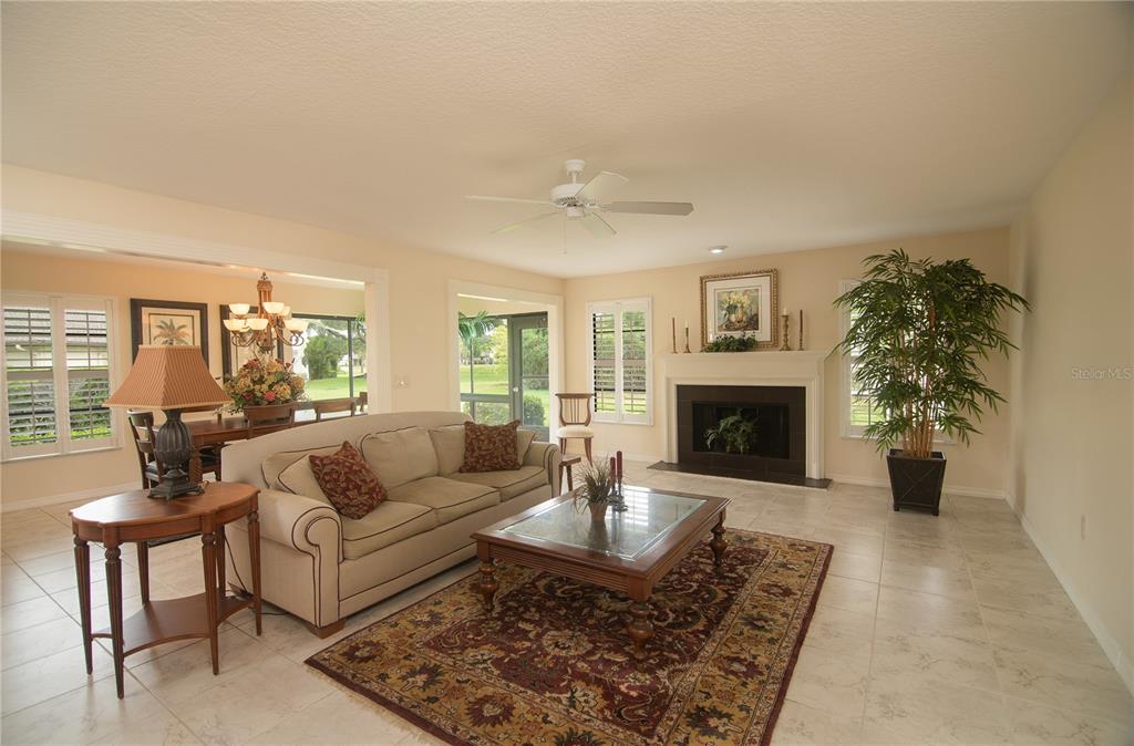 A living room features a beige sofa, a glass-top coffee table, and a fireplace — 7403 CARNOUSTIE DRIVE UNIT 7D, SARASOTA, FL